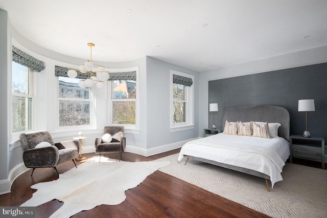 bedroom featuring baseboards, multiple windows, and wood finished floors