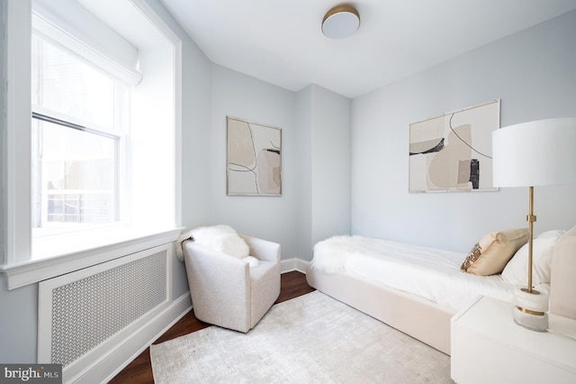 bedroom featuring radiator heating unit, wood finished floors, and baseboards