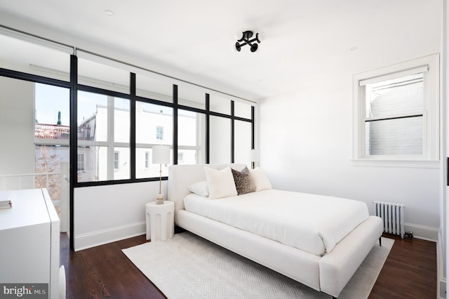 bedroom with dark wood-type flooring, radiator heating unit, and baseboards