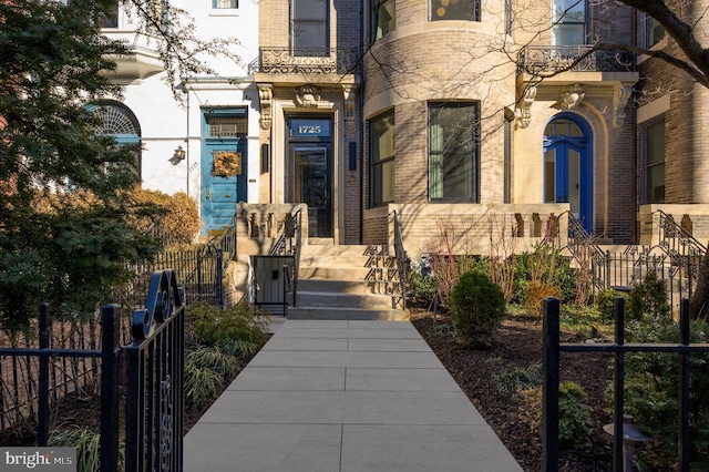 entrance to property featuring fence and brick siding