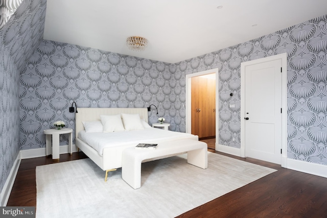 bedroom with baseboards, wood finished floors, and wallpapered walls