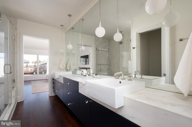 full bath with double vanity, a stall shower, wood finished floors, and a sink