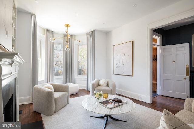 living area featuring baseboards, dark wood-style flooring, and a fireplace