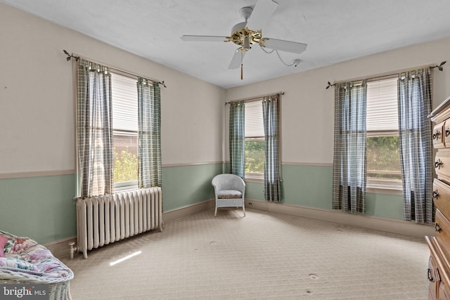 carpeted bedroom with baseboards, radiator, and a ceiling fan
