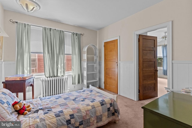 bedroom with carpet floors, a wainscoted wall, and radiator heating unit