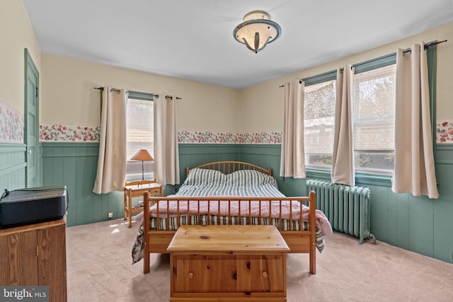 bedroom featuring a wainscoted wall, radiator, carpet flooring, and multiple windows