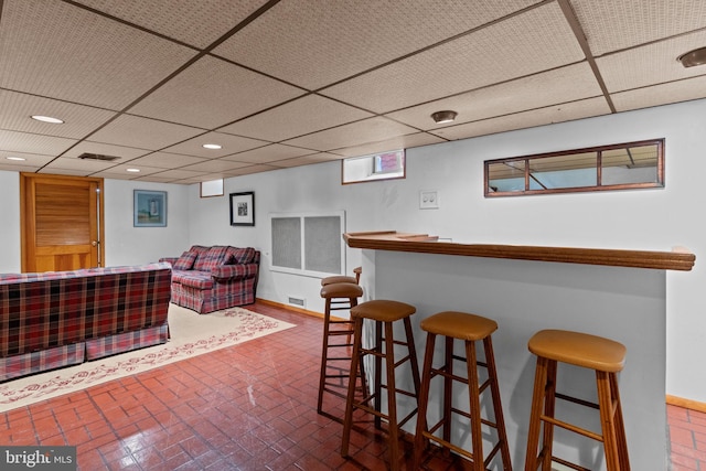 bar featuring a bar, brick patterned floor, visible vents, and a drop ceiling
