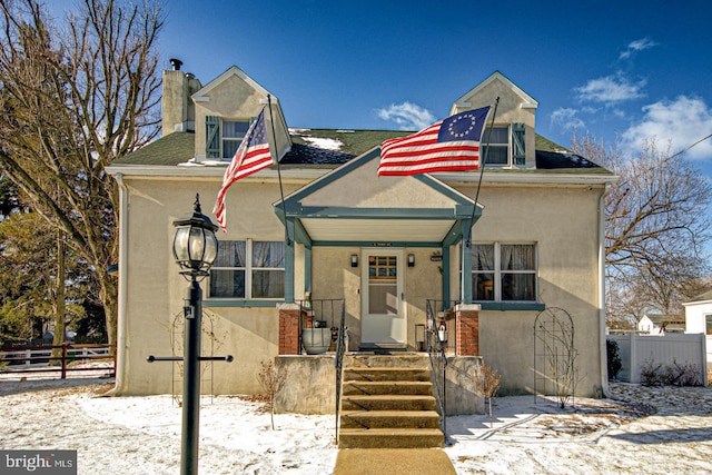 bungalow-style house with a shingled roof, fence, a chimney, and stucco siding