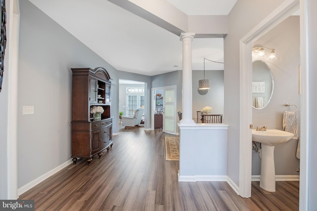 interior space featuring baseboards, dark wood finished floors, and ornate columns