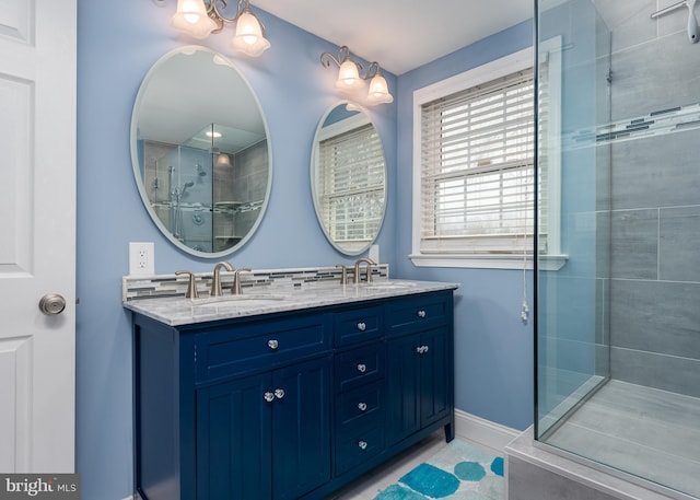 bathroom with double vanity, baseboards, a sink, and tiled shower