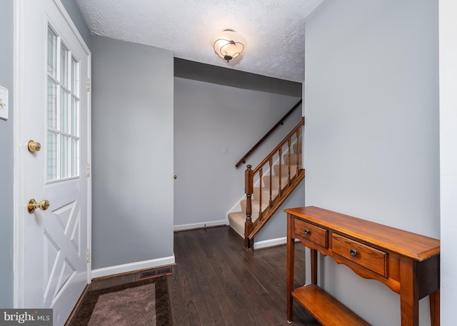 foyer with a textured ceiling, stairway, wood finished floors, and baseboards