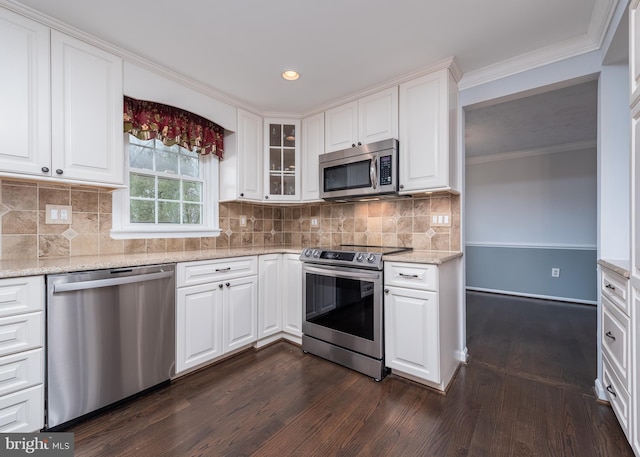 kitchen featuring appliances with stainless steel finishes, light stone counters, dark wood-style flooring, ornamental molding, and white cabinetry