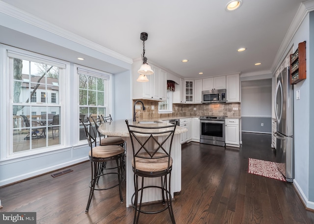 kitchen featuring stainless steel appliances, a peninsula, a sink, visible vents, and white cabinetry