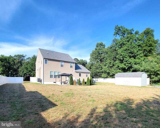 rear view of house with a gazebo, a yard, and a shed