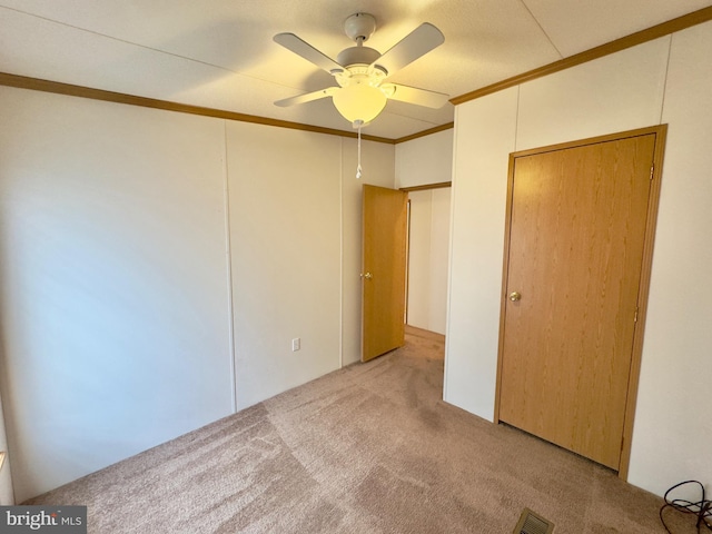 unfurnished bedroom with light carpet, ornamental molding, visible vents, and a ceiling fan