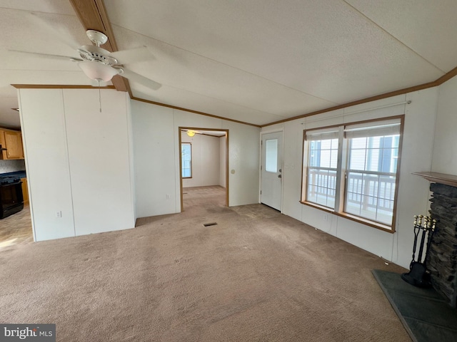 unfurnished living room featuring light carpet, a stone fireplace, ornamental molding, and vaulted ceiling