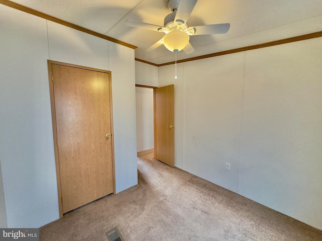 unfurnished bedroom with carpet, visible vents, ceiling fan, and crown molding