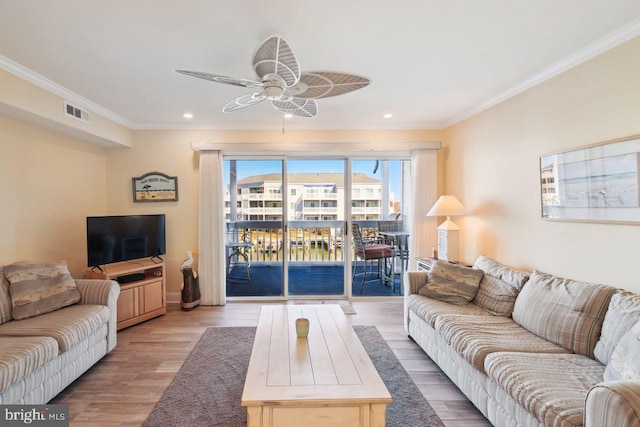 living area with a ceiling fan, visible vents, crown molding, and wood finished floors