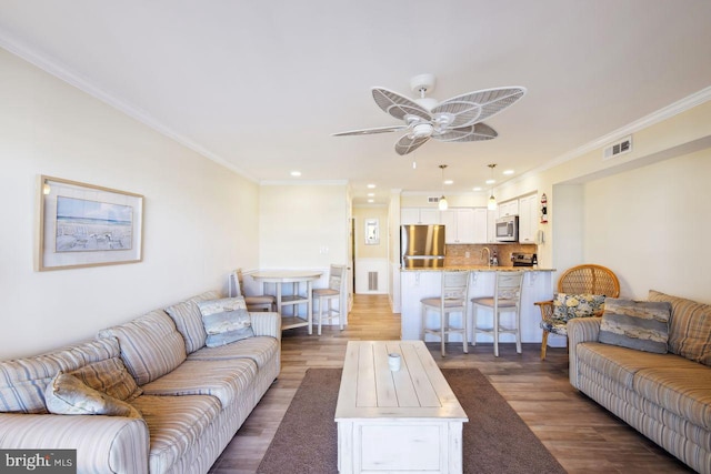 living room featuring dark wood-style floors, ceiling fan, visible vents, and ornamental molding