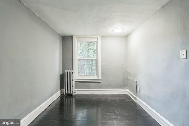 spare room with radiator and dark wood-type flooring