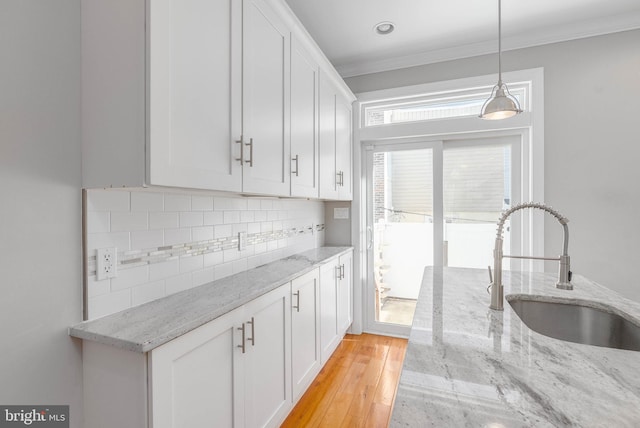 kitchen featuring a sink, white cabinetry, and light stone countertops