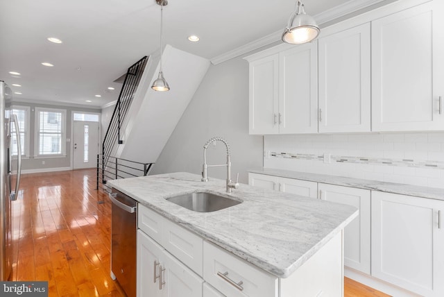 kitchen featuring a sink, white cabinetry, pendant lighting, a kitchen island with sink, and stainless steel appliances