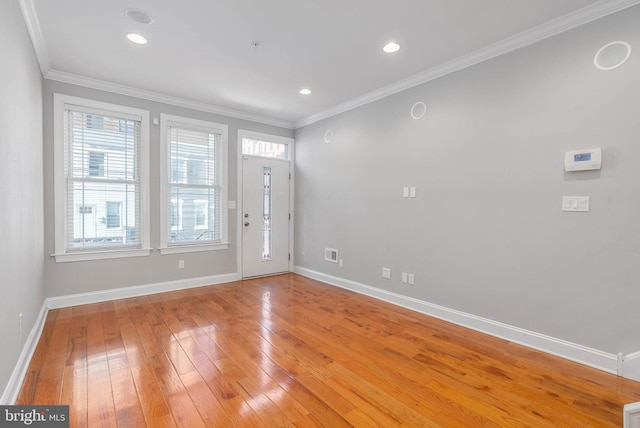 foyer featuring light wood-style flooring, baseboards, crown molding, and visible vents