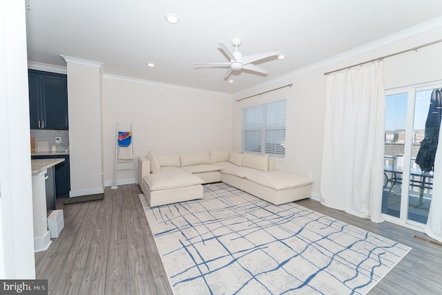 living room featuring recessed lighting, light wood-style flooring, ornamental molding, a ceiling fan, and baseboards