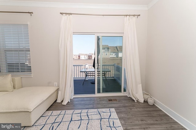 interior space featuring access to exterior, ornamental molding, baseboards, and wood finished floors