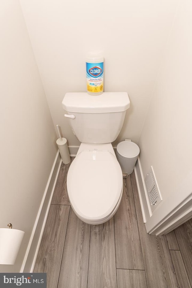 bathroom with wood finish floors, toilet, and baseboards