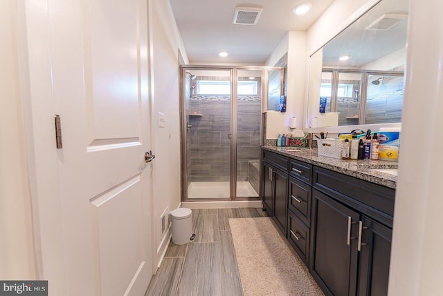 full bathroom with double vanity, a shower stall, visible vents, and a sink