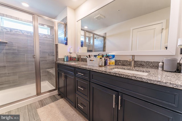 full bath with double vanity, a sink, visible vents, and a shower stall