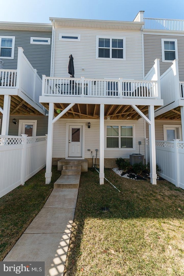 view of front of property with a front lawn, central AC unit, and fence