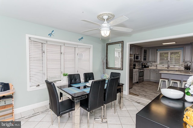 dining area with light tile patterned flooring, a ceiling fan, and baseboards