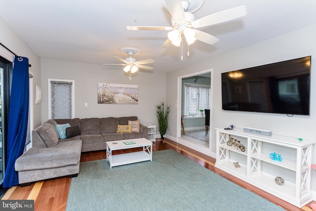 living area featuring ceiling fan, baseboards, and wood finished floors