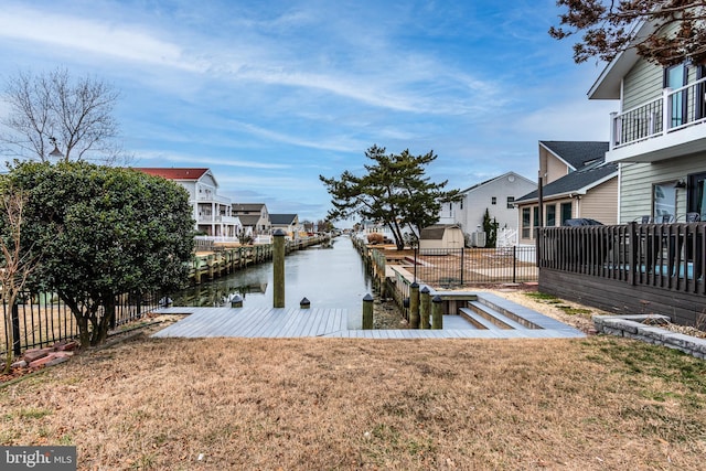 dock area featuring a yard, a water view, fence, and a residential view