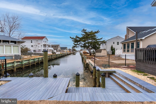 view of dock with a water view, cooling unit, a residential view, and fence