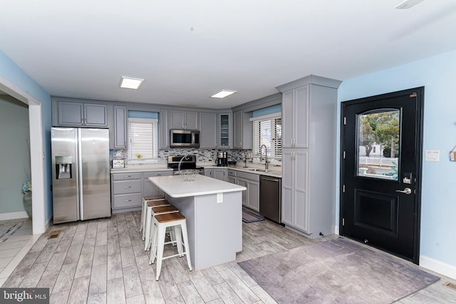 kitchen with stainless steel appliances, a kitchen breakfast bar, light countertops, a center island, and glass insert cabinets