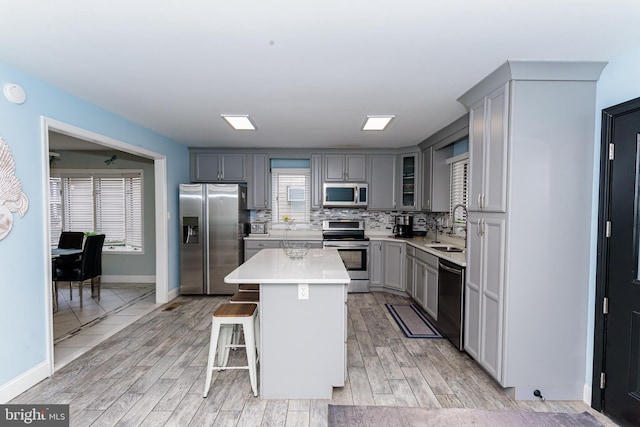 kitchen featuring a center island, a breakfast bar, stainless steel appliances, light countertops, and a sink