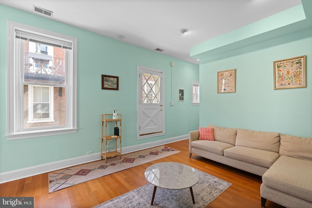 living room with wood finished floors, visible vents, and baseboards