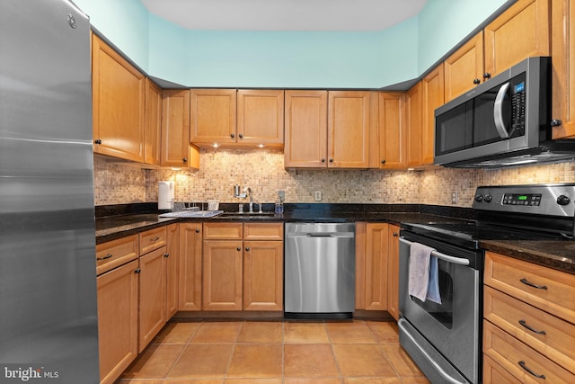 kitchen featuring appliances with stainless steel finishes, dark stone counters, light tile patterned flooring, and tasteful backsplash