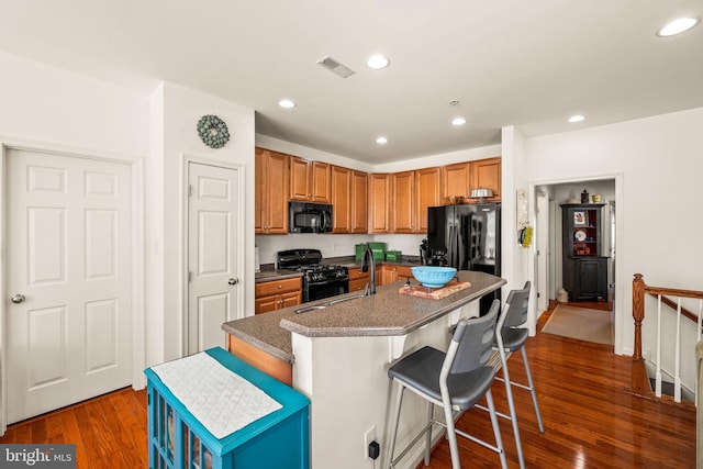 kitchen featuring a kitchen bar, sink, a kitchen island, dark wood-type flooring, and black appliances