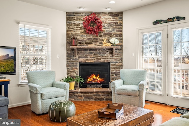 living room with hardwood / wood-style floors and a stone fireplace