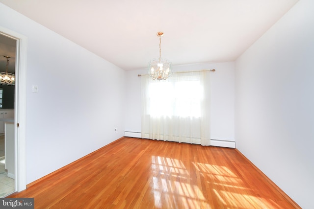 spare room with an inviting chandelier, a baseboard heating unit, and hardwood / wood-style floors