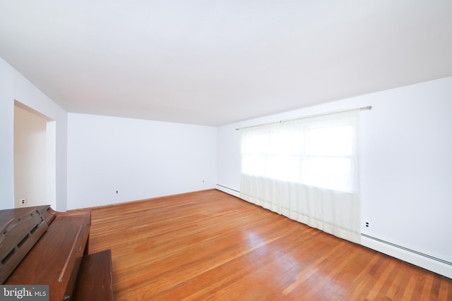 unfurnished room with baseboard heating and wood-type flooring