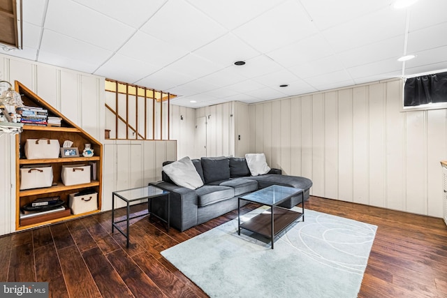 living room with dark wood-type flooring and a drop ceiling