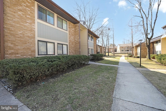 exterior space featuring a residential view, a lawn, and brick siding