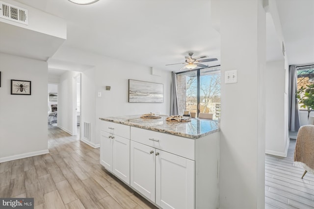 kitchen with light wood-type flooring, white cabinetry, and visible vents