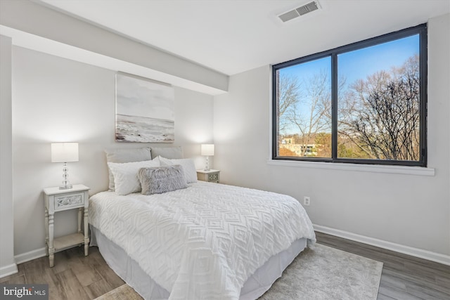 bedroom with wood finished floors, visible vents, and baseboards