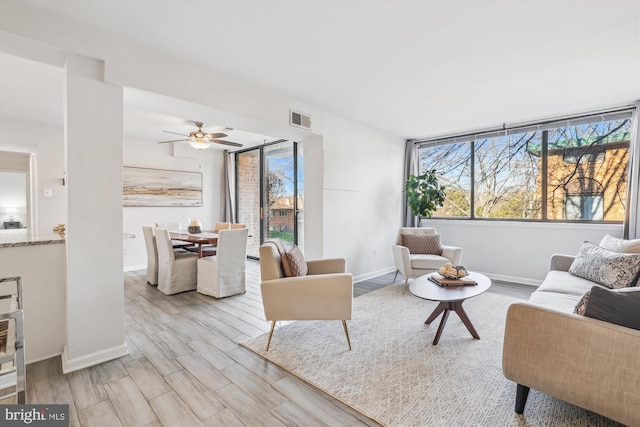 living area with visible vents, plenty of natural light, baseboards, and wood finished floors